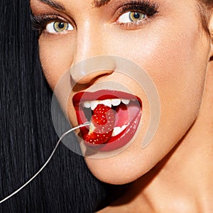 woman with red lips eating strawberry