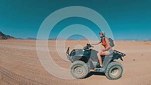 Sexy Woman is Riding a Quad Bike in the Desert of Egypt. Dynamic view in motion.