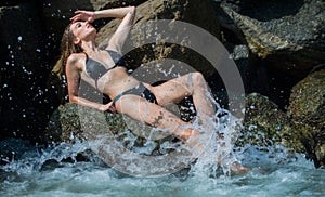 Sexy woman on rocks stone beach. Beautiful girl on sea. Travel and vacation. Sensual beautiful woman with perfect body