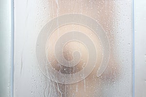 A sexy woman`s buttock is behind the mirror. She is showering a drop of water on her ass photo