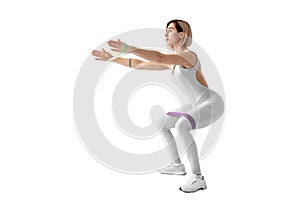 Sexy woman in sportswear using a resistance band in her exercise routine. Young woman performs fitness exercises on