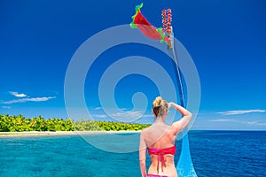 woman standing backwards and watching tropical beach and sea on Maldives island and sea on a traditional Maldivian Dhoni
