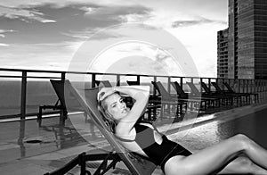 Sexy woman on sunbed near pool. Summer woman. Beautiful sexy woman model in swimsuit bodysuit near swimming pool, posing