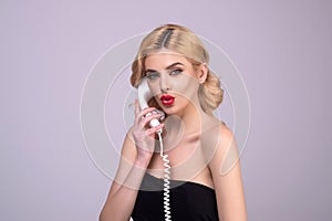 Sexy woman talking on retro line phone. Portrait of woman holding vintage telephone. Pinup girl with phone handset