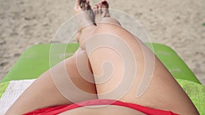 Sexy woman tourist in a bikini sunbathes on a sea beach, closeup