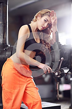 woman weared in orange uniform working by drill machine on the factory.