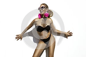 Sexy woman is wearing elegant bikini and luxury sunglasses and is posing on white wall on summer day