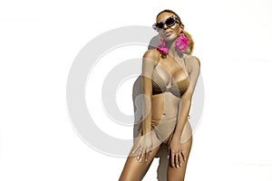 Sexy woman is wearing elegant bikini and luxury sunglasses and is posing on white wall on summer day