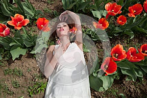 woman in white dress lying in red tulip field