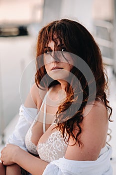 sexy woman in a white shirt enjoys the sunset on her private white yacht