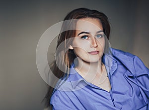 Sexy young beautiful woman with blue big eyes lond hair lying on bed at home in blue shirt photo