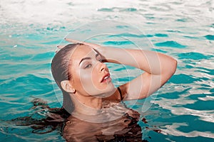 Sexy young beauty swims in the pool alone. Spa and relaxation.