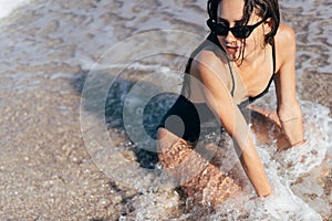 Sexy young brunette posing on her knees in the sea