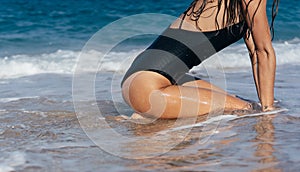 Sexy young brunette posing on her knees in the sea