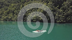 Sexy young brunnette lying down on a paddle board in the middle of atoll lagoon.