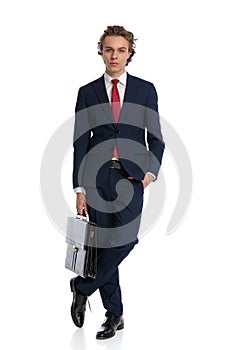 Sexy young businessman holding bag and posing with hand in pocket