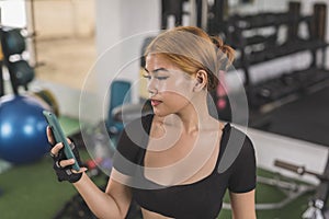 A sexy young filipino asian woman chatting with someone on her phone in between sets at the gym