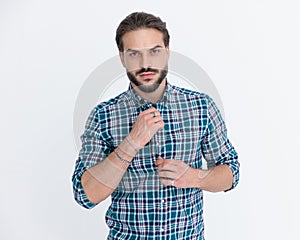 sexy young man with beard unbuttoning casual plaid shirt