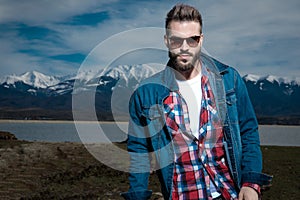 Sexy young man in denim clothes and sunglasses standing outside