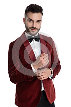 Sexy young man in red velvet tuxedo fixing shirt