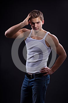 young man wearing white undershirt and jeans, posing over d