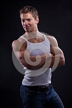 young man wearing white undershirt and jeans, posing over d
