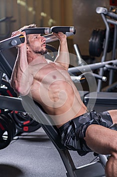 Sexy young muscular man doing upper chest exercise on the machine. Side view