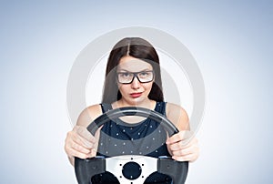 Sexy young smiling happy girl with glasses driving a car, front view