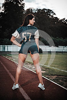 Sexy young sportive girls in t-shirt of rugby football player in action on the stadium. American football woman player stay on
