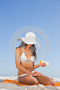 Mladá žena použitie slnko krém zatiaľ čo na jej uterák 