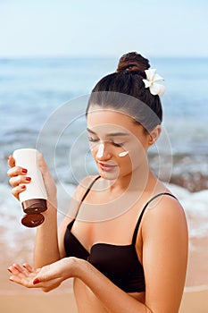 Sexy Young Woman in Bikini  Holding  Bottles of Sunscreen in Her Hands. Skin care. A Female  Applying Sun Cream Creme