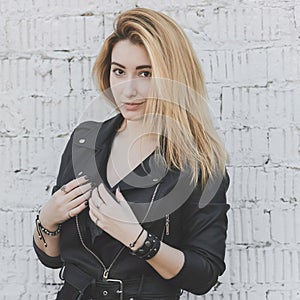 Sexy young woman in black eco leather jacket and volume hairstyle