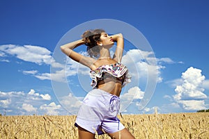 young woman in blue shorts in a wheat golden field