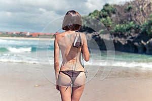 young woman without bra on the tropical beach of Bali island. Bikini girl freedom concept. Indonesia.