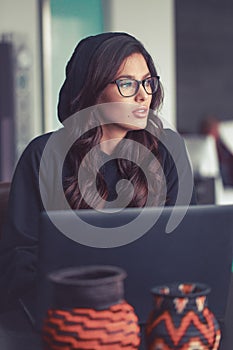 Sexy young woman in hoodie looking away at laptop