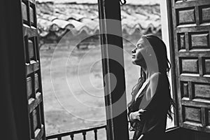 young woman in lingerie posing near a window