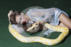 Sexy young woman posing with albino python against green background