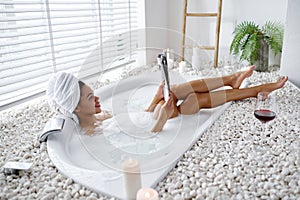 Sexy young woman reads a magazine in a bubble bath