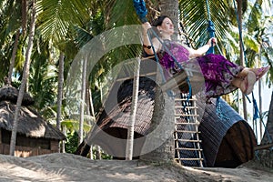 young woman sitting on the swing on the tropical beach, paradise island Bali, Indonesia. Sunny day, happy vacation