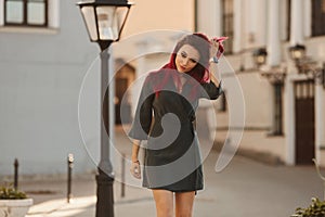 Sexy young woman with slim perfect body and pink hair in a short dress walking on the street. Fashion portrait of model