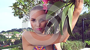 young woman wearing bikini with wet hair and tree flower on a sunny day