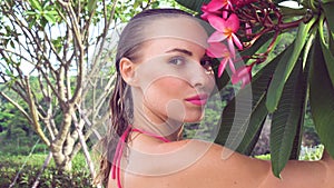 young woman wearing bikini with wet hair and tree flower on a sunny day