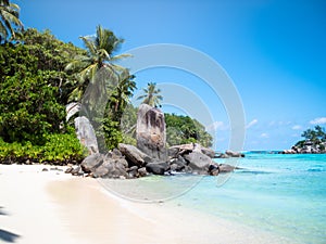 Seychelles beach with exposed rocks and distant island