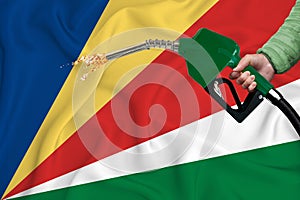 SEYCHELLES flag Close-up shot on waving background texture with Fuel pump nozzle in hand. The concept of design solutions. 3d