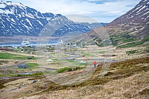 Seydisfjordur landscape with snow mountain and AIDA cruise ship at the horizon, wide angle shot, natural landscape, people hiking