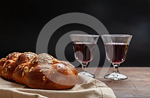 Challah bread with two glasses of red wine on wooden table