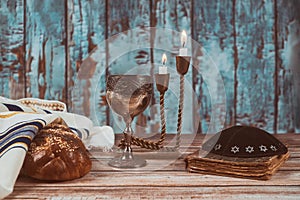 Shabbat eve table candles and cup of wine with covered challah bread