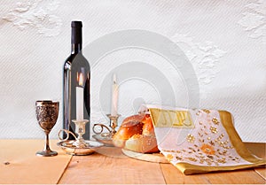 Shabbat image. challah bread, shabbat wine and candelas on wooden table.