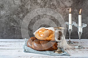 Shabbat Shalom - challah bread, shabbat wine and candles on grey background. With copy space