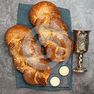Shabbat Shalom - challah bread, shabbat wine and candles on grey background. Top view